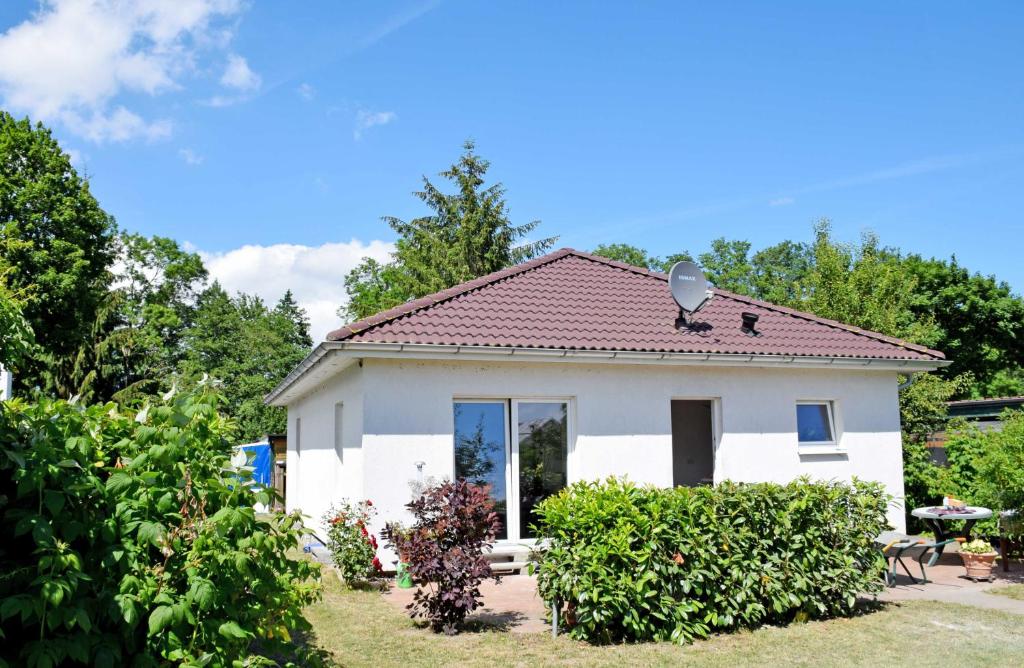 a small white house in a yard with bushes at Ferienhaus Falkenhagen mit Garten in Pachthof