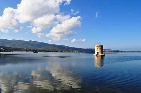 a building in the middle of a large body of water at Cinema House Apartments in Orbetello