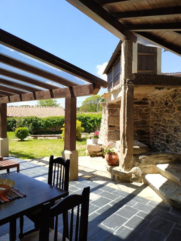 Casa Roan y Casa Grande في Lodoso: فناء مع طاولة وكراسي وجدار حجري