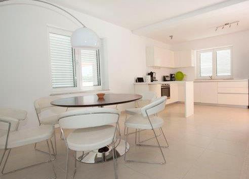 a white kitchen with a table and white chairs at Villa Matovica in Kampor