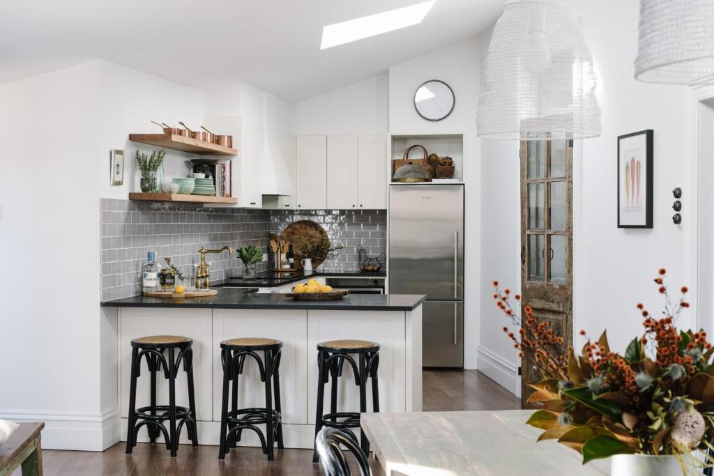 a kitchen with white cabinets and bar stools at Raffah House in Oatlands