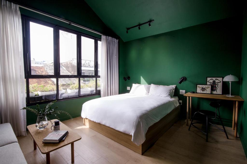 a green bedroom with a bed and a table at Botanist Lab Minihotel by CIRCADIAN in Ho Chi Minh City