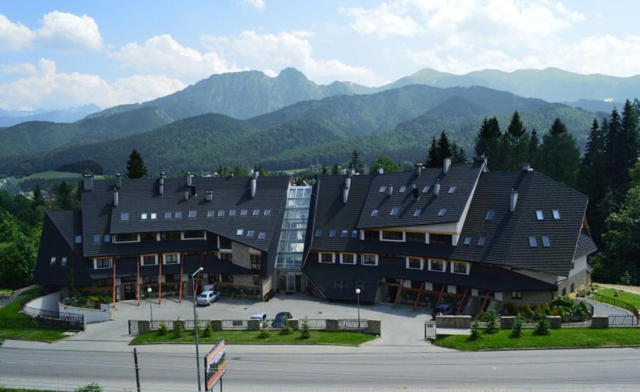 a large building with mountains in the background at BUTOROWY RESIDENCE Apartament "GÓRSKA ORCHIDEA" in Kościelisko