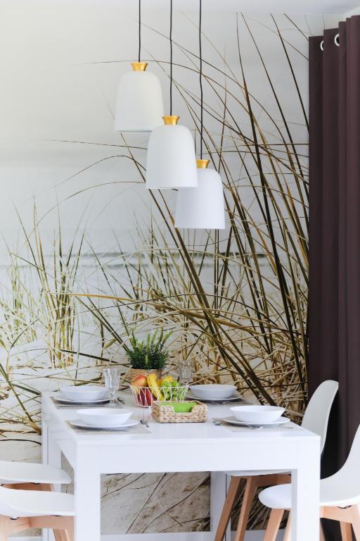 a white dining room table with white chairs and a white tablestration at M&K Apartamenty - Morska Bryza, Sobieszewo- Wyspa Sobieszewwska in Gdańsk