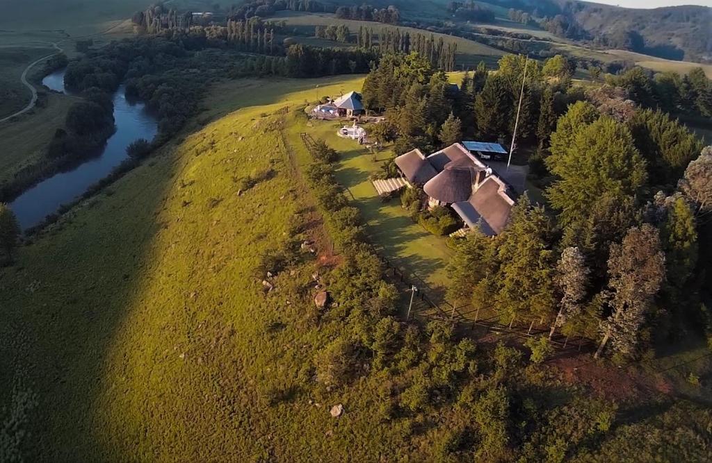 an aerial view of a house on a hill next to a river at Amazian Mountain River Lodge in Underberg