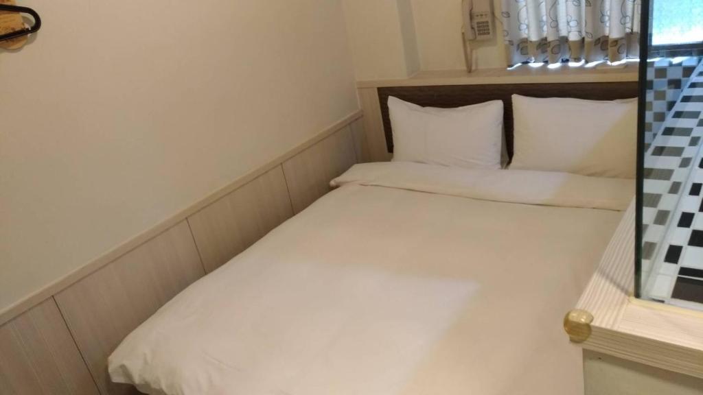 a small bed with white sheets and pillows in a room at Galaxy Mini Inn in Taipei