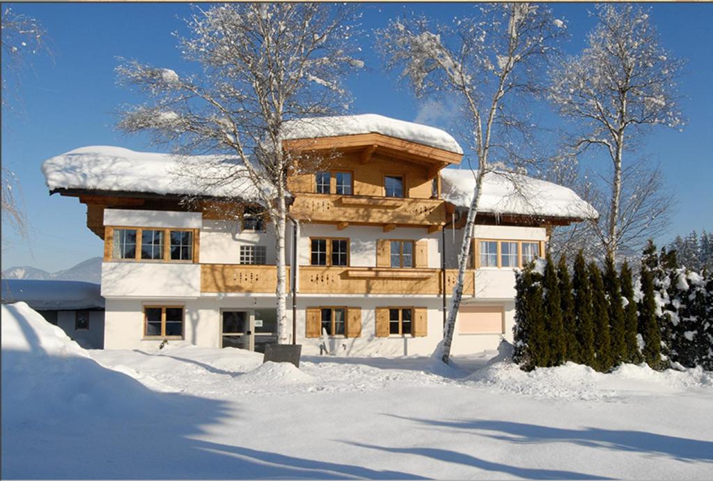 una casa cubierta de nieve delante en Appartement Steinbock, en Sankt Johann in Tirol