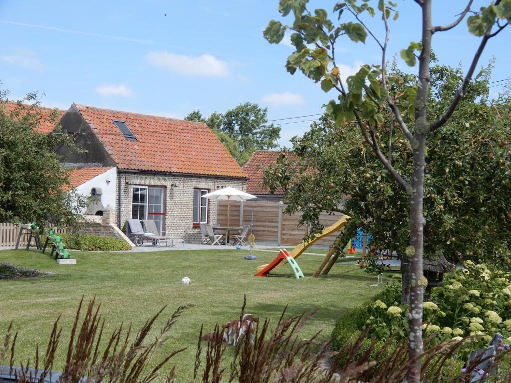 a yard with a playground and a house at Holiday Home Cuylehoeve in Leffinge