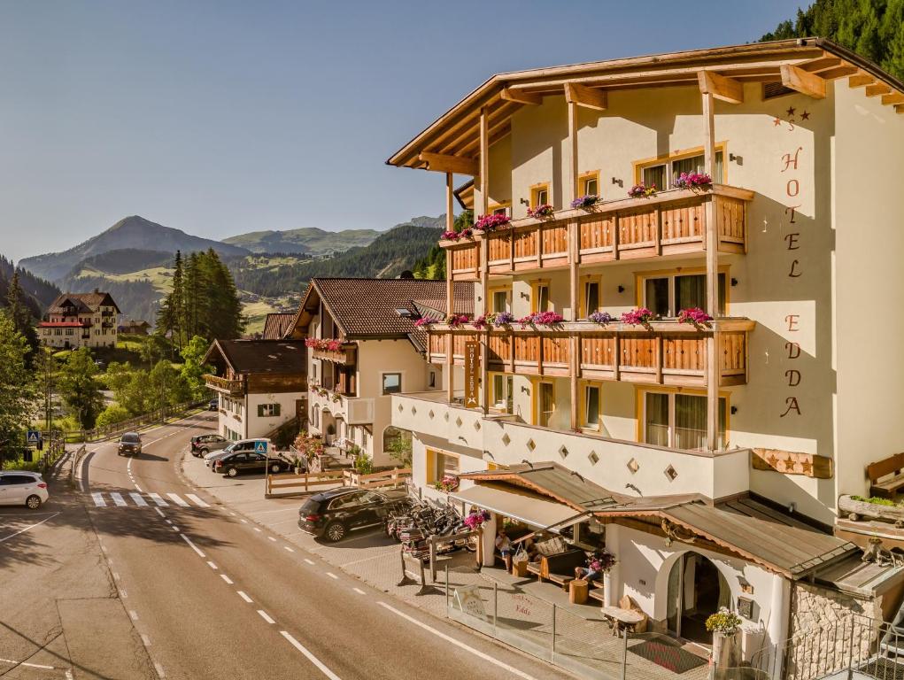 ein großes Gebäude mit Blumen auf den Balkonen an einer Straße in der Unterkunft Hotel Edda in Wolkenstein in Gröden