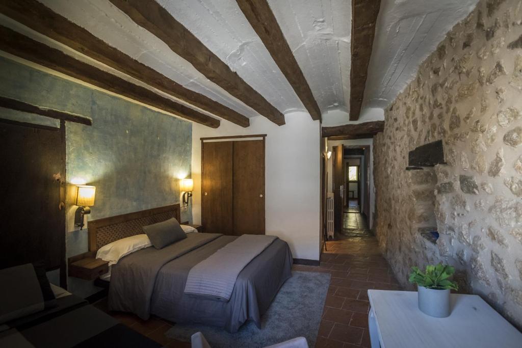 1 dormitorio con cama y pared de piedra en Alojamiento Rural Font del Roser en Chiva de Morella
