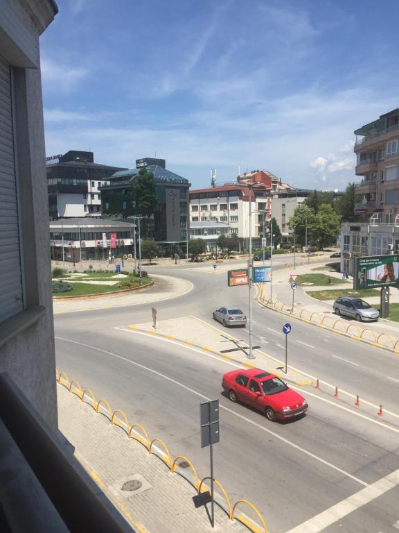 ein rotes Auto, das eine Stadtstraße mit Gebäuden entlangfährt in der Unterkunft Ohrid Strict Center Apartment in Ohrid