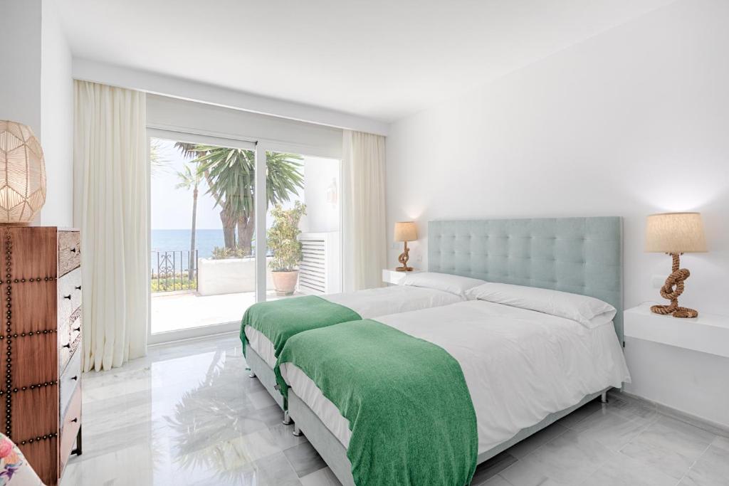 ein weißes Schlafzimmer mit einem Bett mit einer grünen Decke in der Unterkunft Hanami Alcazaba Beach Front Sea View in Estepona