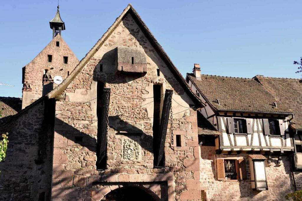 an old stone building with a clock tower at Le B. VINTAGE in Riquewihr