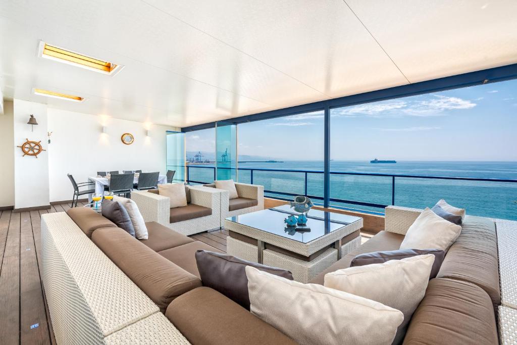 ein Wohnzimmer mit großer Couch und Blick auf das Meer in der Unterkunft iloftmalaga Ático Pacífico 19 A in Málaga