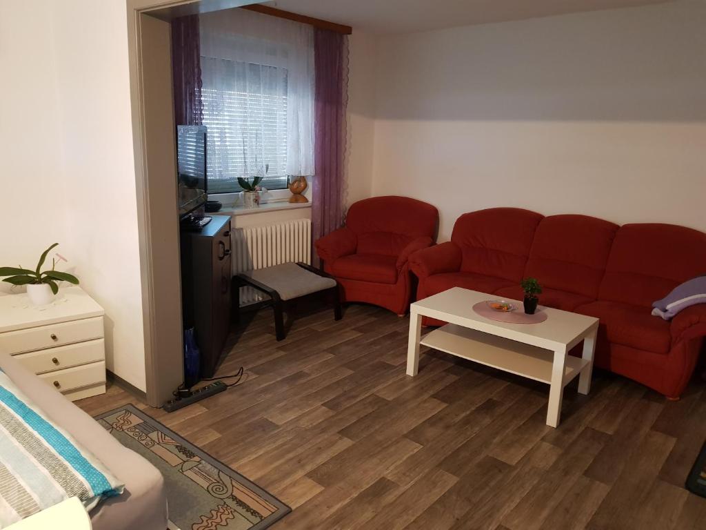 una sala de estar con 2 sofás rojos y una mesa. en Ferienwohnung Eliah, en Rust