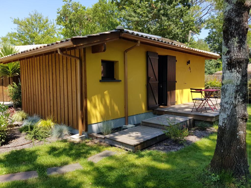 a yellow tiny house with a deck and a table at Salamandre et Hippocampe in Lanton