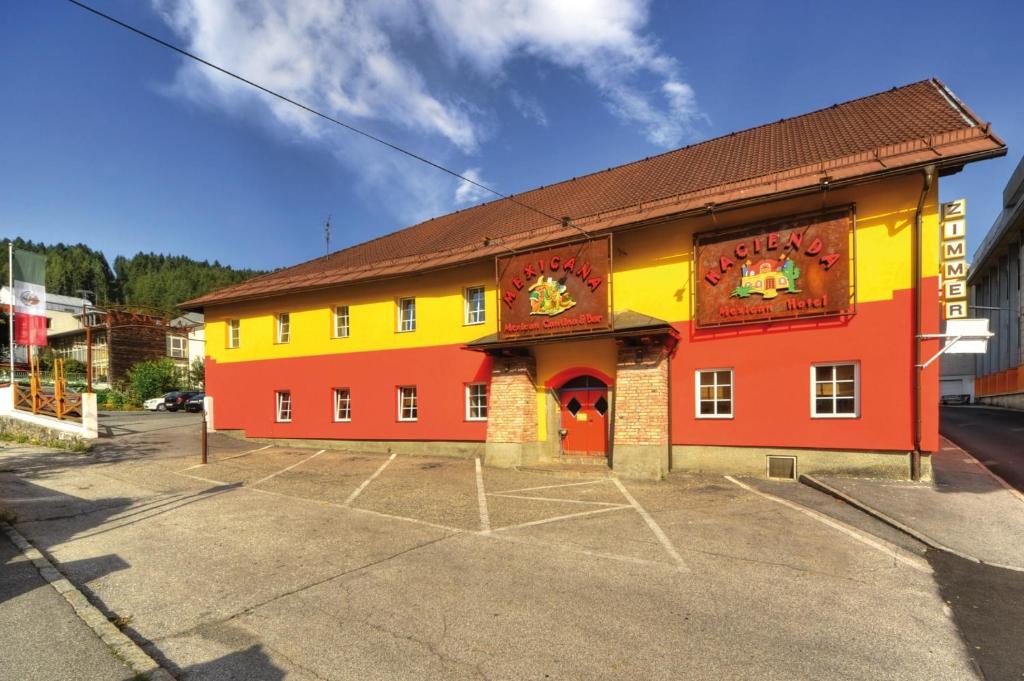 ein gelbes und orangefarbenes Gebäude auf einem Parkplatz in der Unterkunft Hacienda Mexicana in Spittal an der Drau