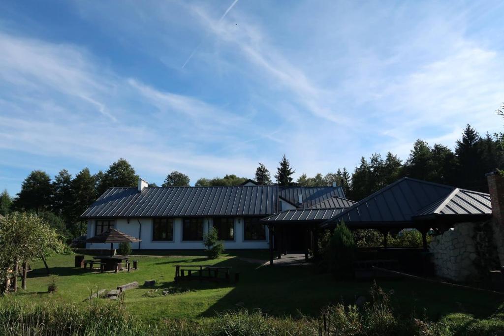 ein weißes Haus mit schwarzen Dächern und einem Hof in der Unterkunft Agroturystyka Kresówka in Lubycza Królewska