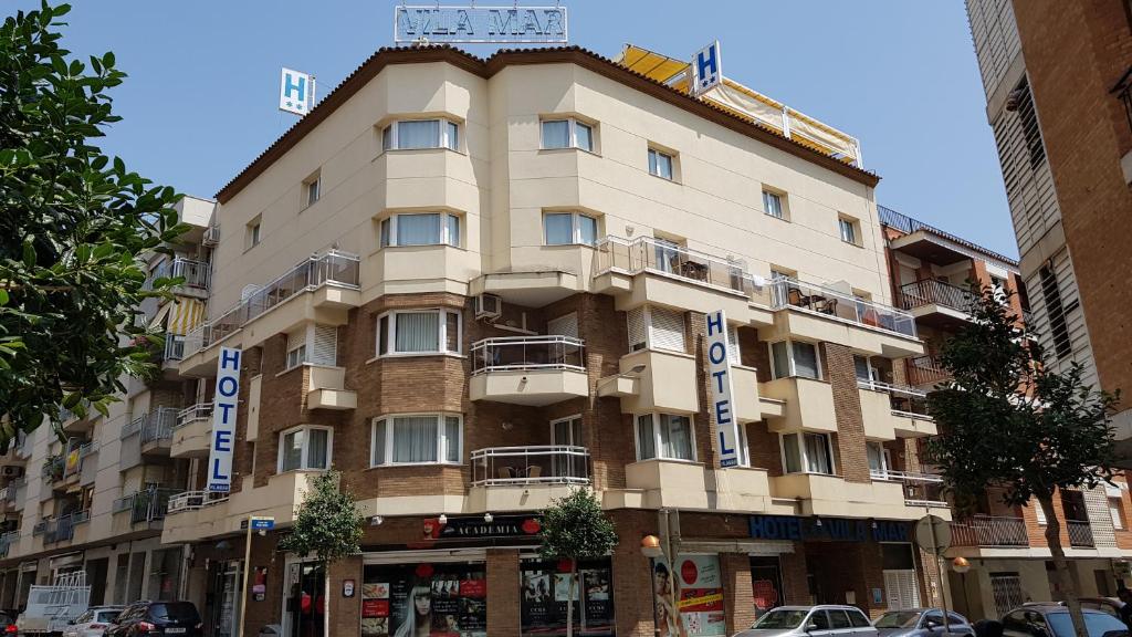 a large building on a street with cars parked in front at Hotel Vila Mar in Cambrils