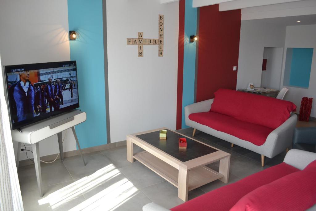 ein Wohnzimmer mit einem roten Sofa und einem Fernseher in der Unterkunft L'EDEN DE LA HAUTE FORET in Mervent