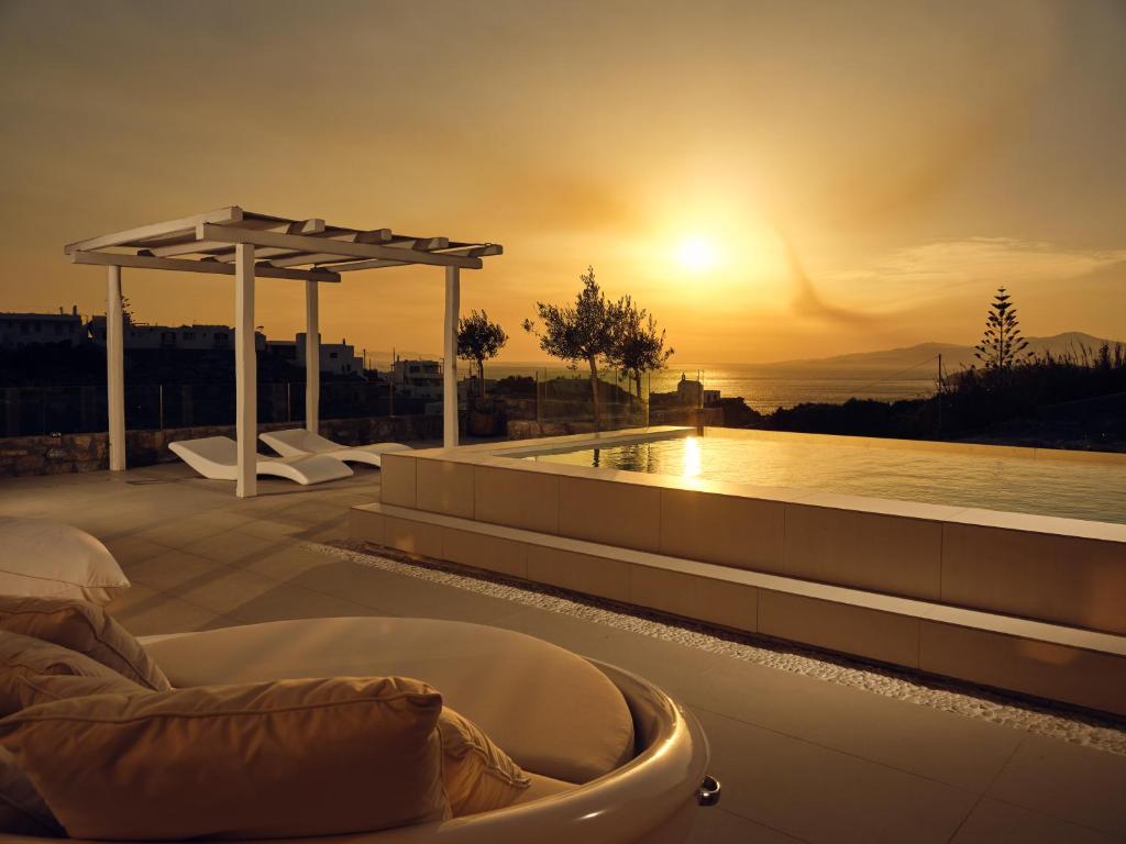 Arcs Boutique Villa Hotel في مدينة ميكونوس: حوض استحمام ساخن على السطح مع غروب الشمس في الخلفية