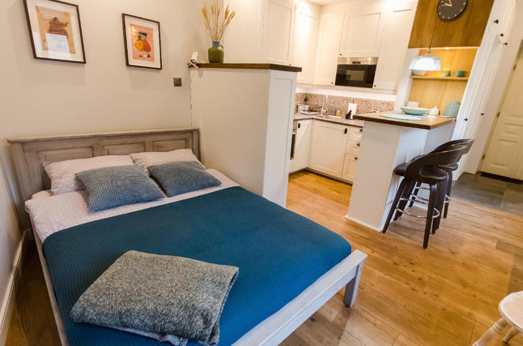 um quarto com uma cama com lençóis azuis e uma cozinha em Apartament EmeryK em Cracóvia