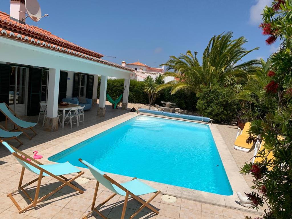 a swimming pool with two chairs and a house at Holiday villa with pool near the ocean in Aljezur