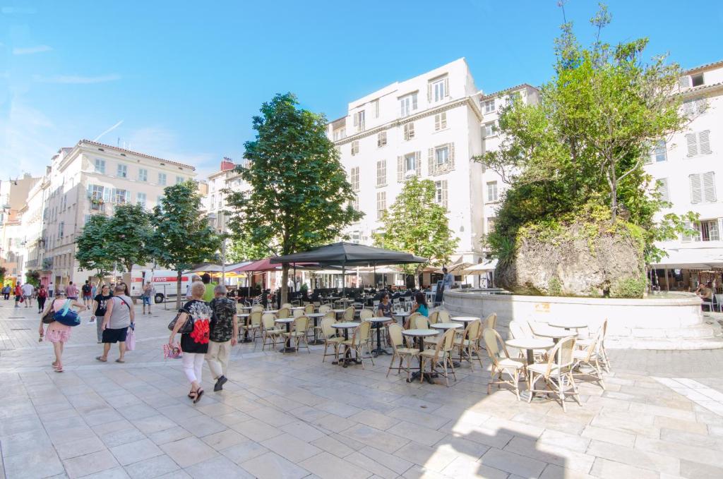 a group of people walking down a street with tables and chairs at Résidence La Source in Toulon