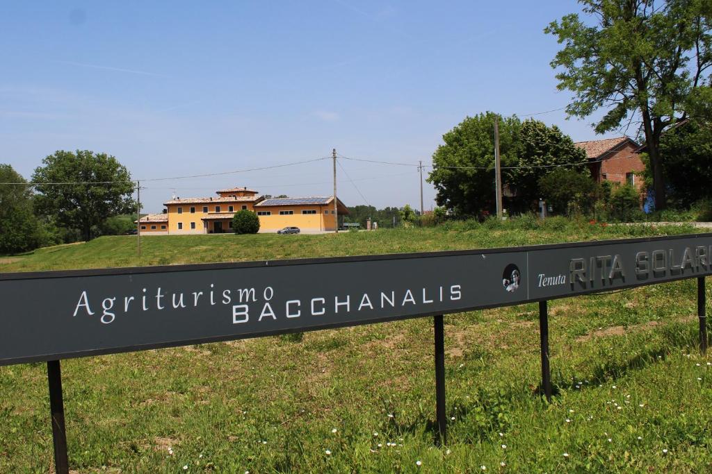 a sign in a field with a building in the background at Agriturismo Bacchanalis in Ziano Piacentino