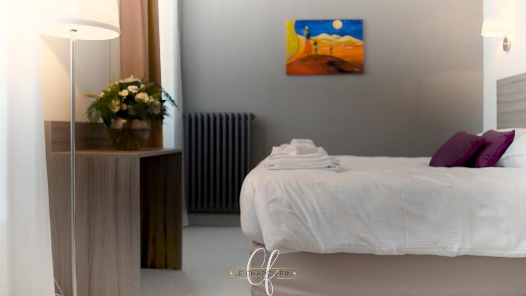 Un dormitorio con una cama y una mesa con un jarrón de flores en HÔTEL LE CHAPON FIN, en Moissac