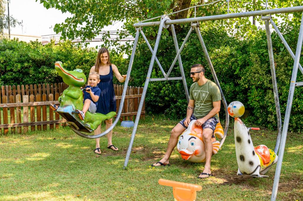a man and a woman and a child on a swing at Hotel St Gregory Park in Rimini