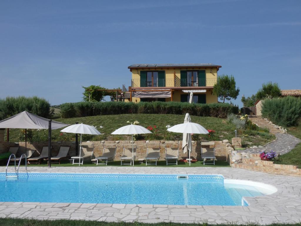 una piscina con sillas y sombrillas frente a una casa en Il Frutteto Bed and Breakfast, en Ripattone