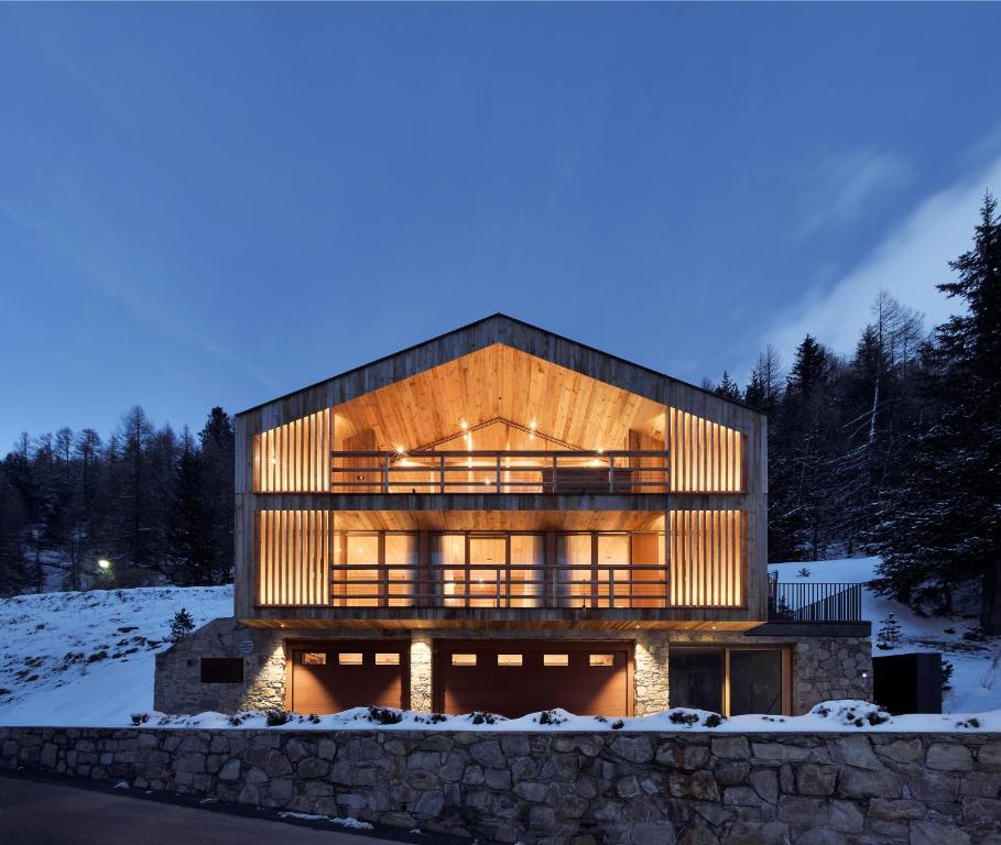 a large house with wooden facade in the snow at Chalet Ourtls Pärg in Solda