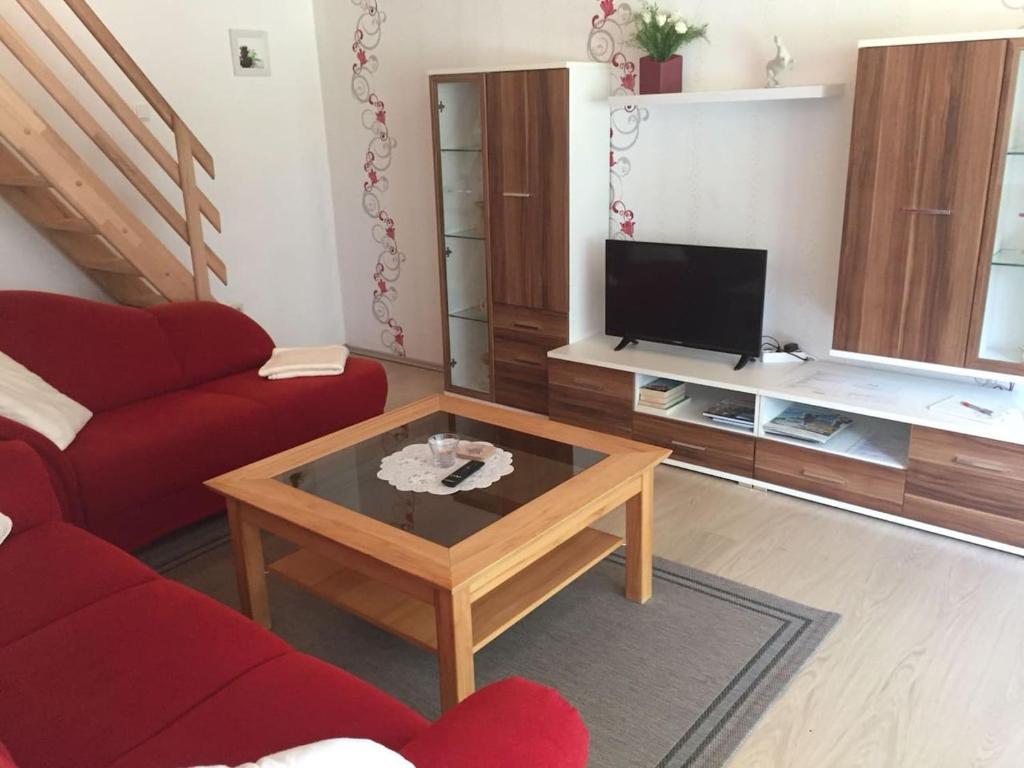 a living room with a red couch and a coffee table at Ferienwohnung bi Klatt tu Hus in Wremen