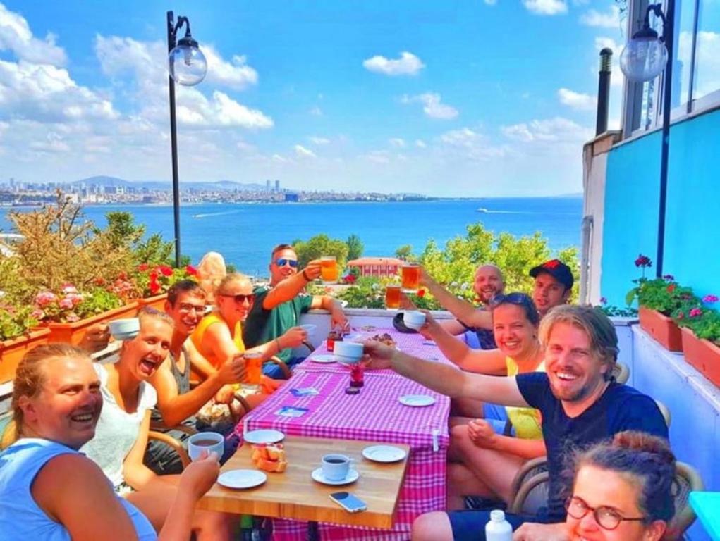 een groep mensen die rond een tafel zitten met drankjes bij Cheers Vintage Hostel in Istanbul
