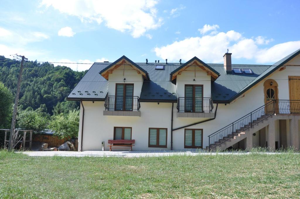 Una gran casa blanca con persianas verdes. en Agroturystyka Królowo, en Tylmanowa