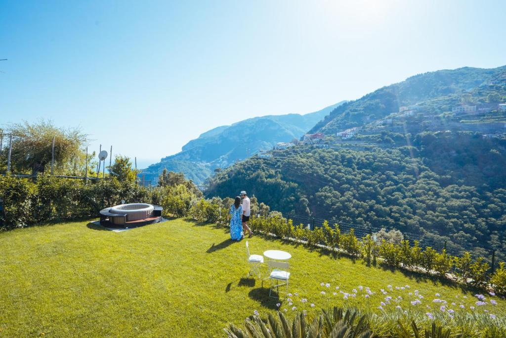 a person standing on a field with mountains in the background at Chez Lia - Private garden and tub, sea view close to Villa Eva and Cimbrone, Ravello in Ravello