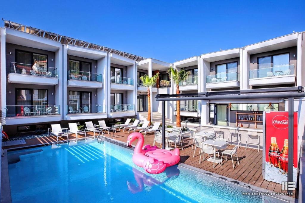 a swimming pool with a pink flamingo in front of a building at Senso Suites in Néa Péramos