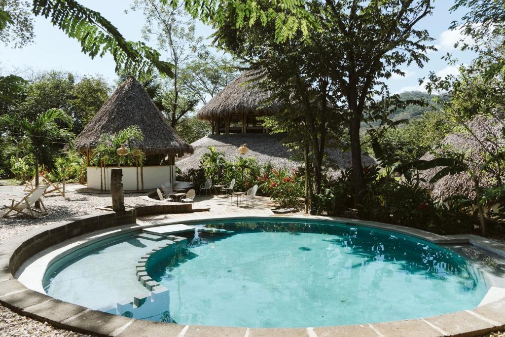 una piscina di fronte a una casa con capanna di Dreamsea Surf Resort Nicaragua a San Juan del Sur