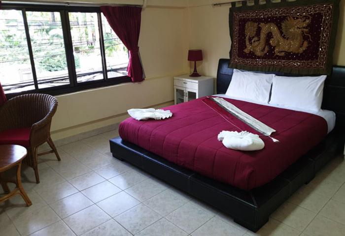 a bedroom with a large bed with two towels on it at Oasis Guesthouse & Bar in Karon Beach