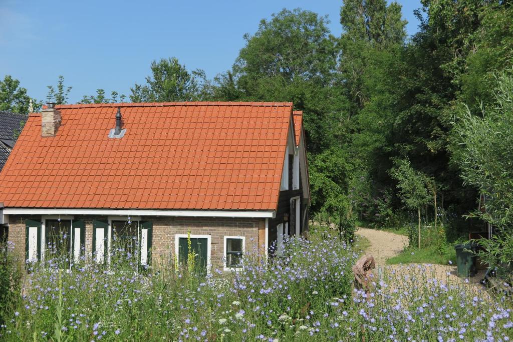 ein Haus mit einem orangenen Dach und einem Blumenfeld in der Unterkunft Het Kunstenaarshuis in Kamperland