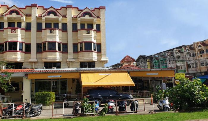 um edifício com um carro estacionado em frente em Oasis Apartments & Bar em Praia de Karon