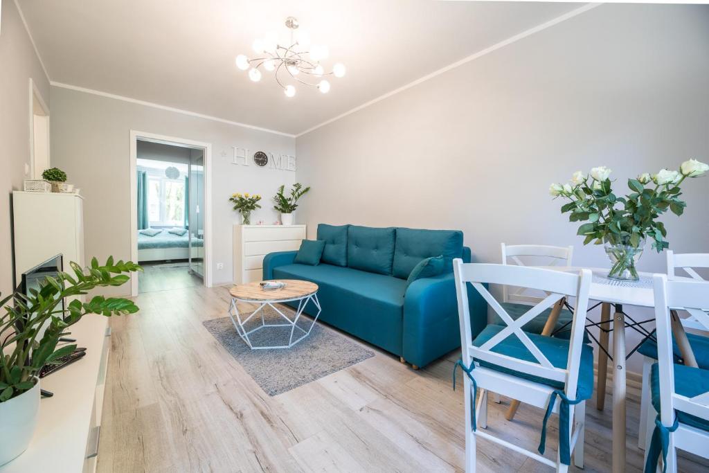 uma sala de estar com um sofá azul e uma mesa em Apartament uJasia em Słupsk