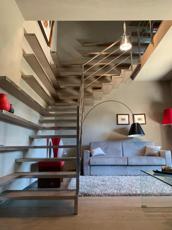 een woonkamer met een blauwe bank en een trap bij Exclusive Loft by the sea 400mt in Forte dei Marmi