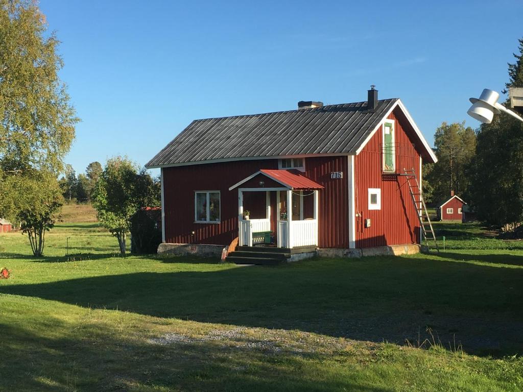 um celeiro vermelho sentado em cima de um campo verde exuberante em Grindstugan på Fyrås Gård em Hammerdal