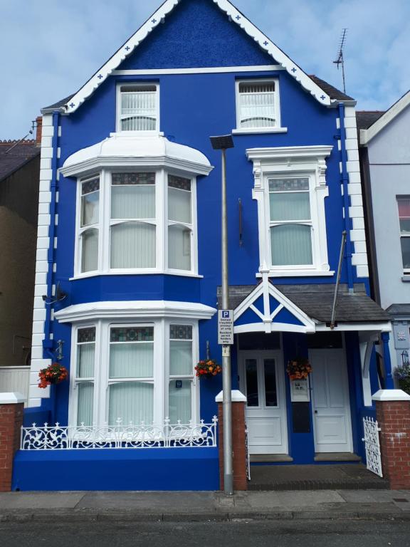 ein blaues Haus mit weißen Fenstern auf einer Straße in der Unterkunft Glenholme Apartments in Tenby
