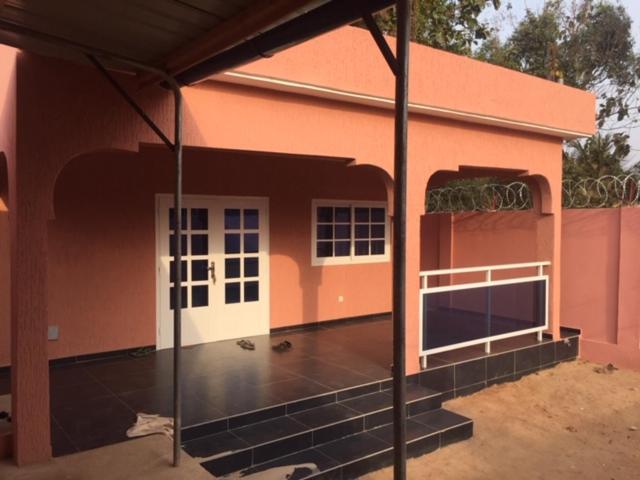 ein rosafarbenes Haus mit einer weißen Tür und einer Garage in der Unterkunft MINI VILLA ROSE in Lomé