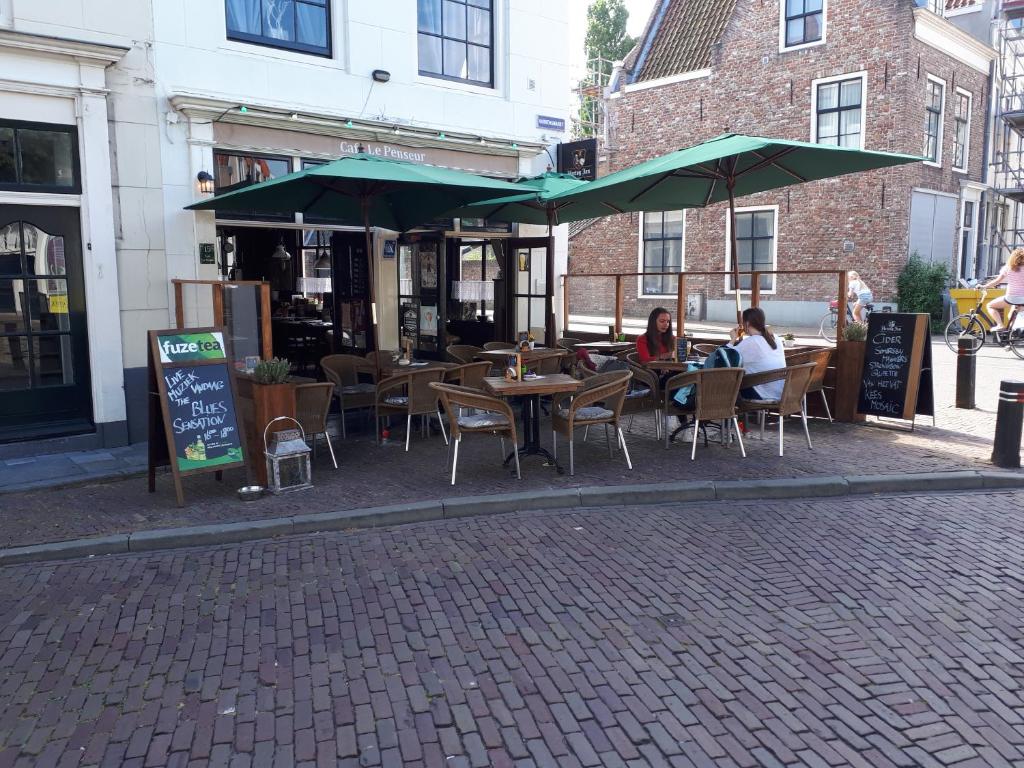 twee mensen aan tafel met paraplu's op straat bij Le Penseur in Middelburg