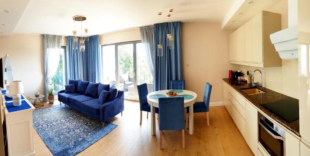 a kitchen and living room with blue chairs and a table at Apartament North Coast - nad morzem in Gdańsk
