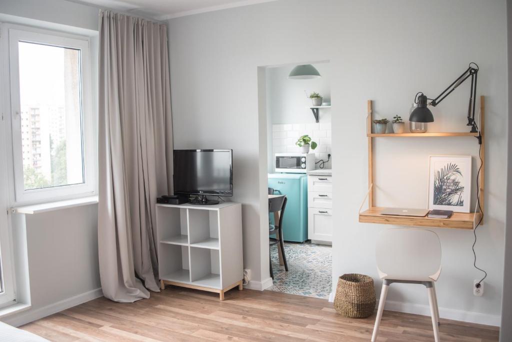 een woonkamer met een televisie en een bureau met een stoel bij TS Budget Stay in Szczecin